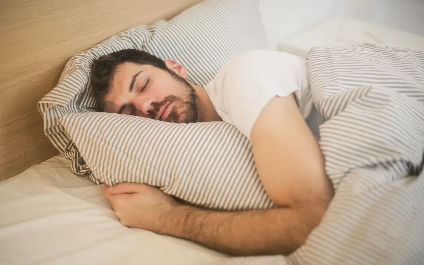 Muž klidně spí na pruhovaném povlečení